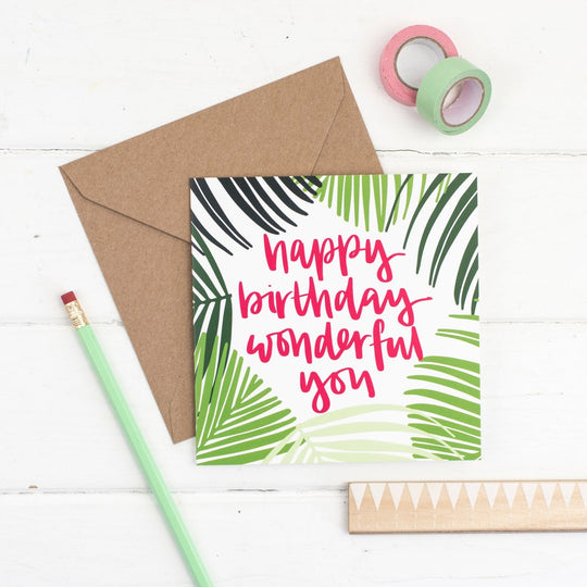 Happy birthday wonderful you raspberry lettering and a hand drawn palm frond illustration square card with kraft envelope