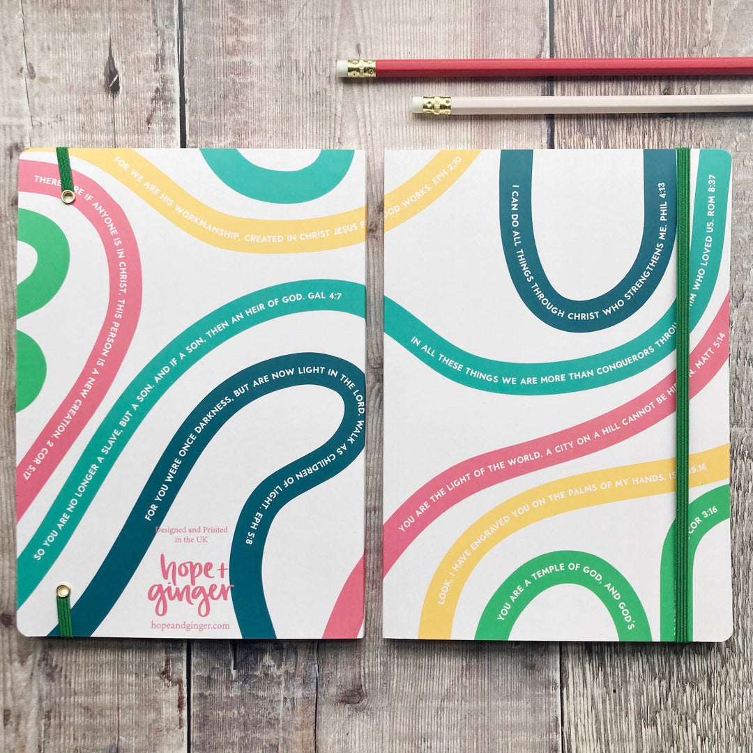 Two colorful notebooks with text on a wooden surface, featuring the brand 'Hope + Ginger'.