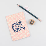 A6 mini devotional notebook be still and know hand lettered on peach colour with a hand drawn flower repeated illustration
