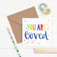 Brightly coloured hand lettered you are loved square greeting card with hand drawn triangle confetti illustration