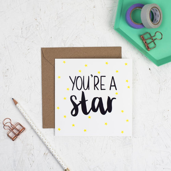 You're a star hand lettered square greeting card with black lettering and illustrated yellow stars